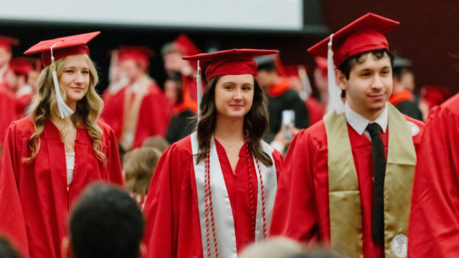 Image shows a group of graduating students in red cap and gowns.