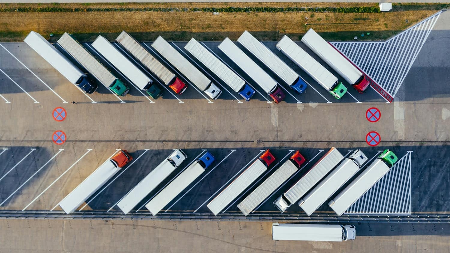 an aerial view of dozens of tractor trailers parked at a distribution center